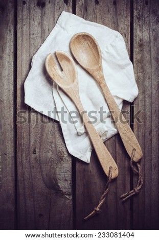 New clean wooden spoons and napkin on old wooden kitchen board, cooking background