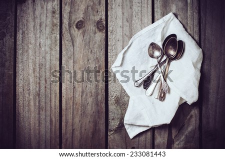Old vintage cupronickel spoons and napkin on old wooden board, silverware