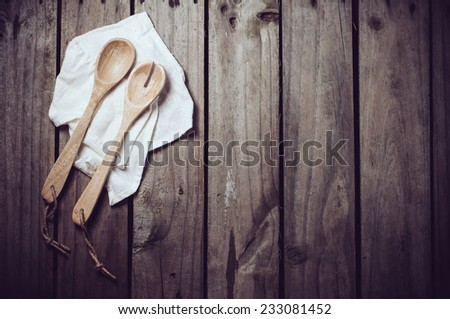 New clean wooden spoons and napkin on old wooden kitchen board, cooking background
