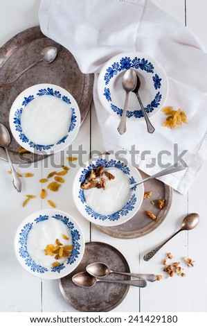 Natural yogurt, dairy products in white plates with blue ornaments, napkins, trays and vintage cutlery on a white board, rustic food.