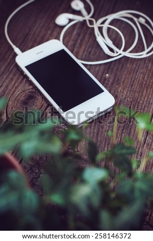 White smartphone with headphones on an old wooden board