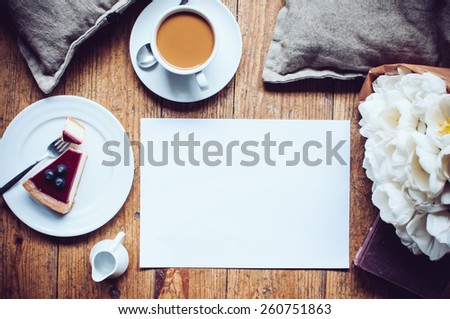Pillows, a bouquet of tulips, coffee with milk, cheesecake, paper note pad on a shabby wooden floor. Hipster lifestyle