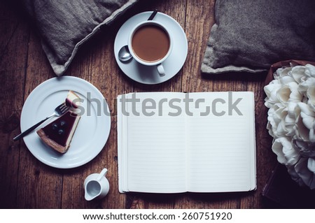 Pillows, a bouquet of tulips, coffee with milk, cheesecake, paper note pad on a shabby wooden floor. Hipster lifestyle
