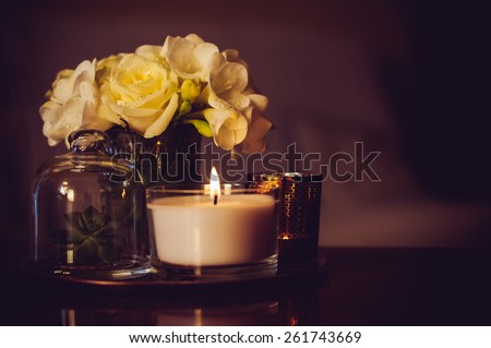 Bouquet of flowers in a vase, candles on a tray, vintage home decor on an a table, dark tones