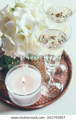 Bouquet of white flowers in a vase, candles and champagne on a copper tray vintage, wedding home decor