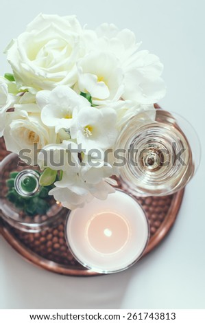 Bouquet of white flowers in a vase, candles and champagne on a copper tray vintage, wedding home decor