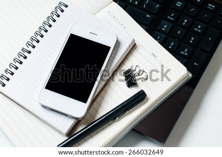Office tabletop, home office: a laptop, notebooks, reading glasses, smart phone, pen on a white background