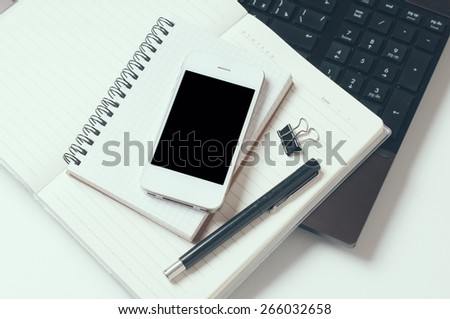 Office tabletop, home office: a laptop, notebooks, reading glasses, smart phone, pen on a white background