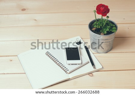 Rustic tabletop, home office: notebooks, smart phone, pen and a flower