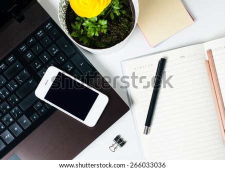 Desktop, home office: a laptop, notebooks, glasses, smart phone, flower, pens and pencils on a white background