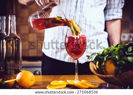 Man pours homemade sangria with fruit pieces in a glass. Refreshing summer drinks