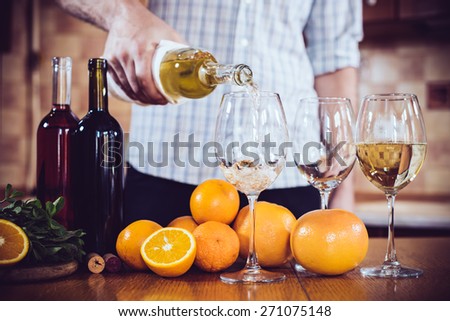 Man pours white wine from a bottle into a glass, home kitchen interior, wine party.