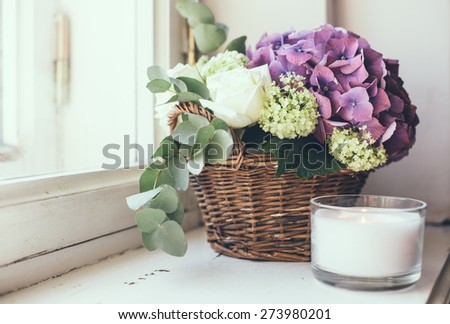 Big bouquet of fresh flowers, purple hydrangeas and white roses in a wicker basket on a windowsill, home decor, vintage style