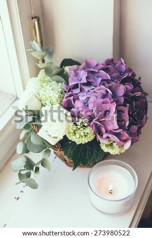 Big bouquet of fresh flowers, purple hydrangeas and white roses in a wicker basket on a windowsill, home decor, vintage style