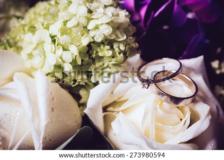 Big bouquet of fresh flowers, purple hydrangeas and white roses and wedding rings closeup