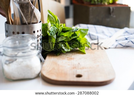 A bunch of basil on the board on the kitchen table, home kitchen supplies for cooking.