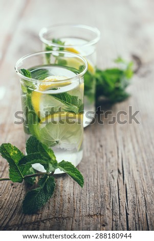Homemade lemonade refreshing summer detox drink made from lemon and mint in glasses on old vintage wooden board.