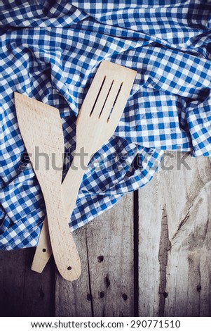 Two wooden spatulas and blue linen cloth on an old wooden board, vintage kitchen background