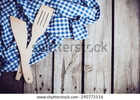Two wooden spatulas and blue linen cloth on an old wooden board, vintage kitchen background