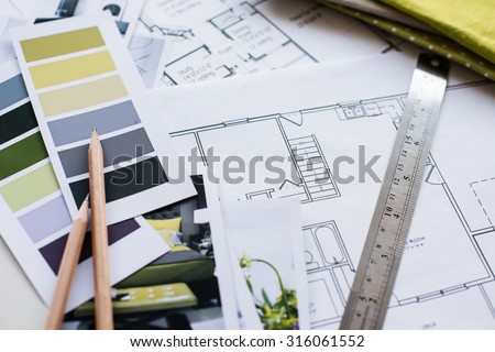 Interior designer\'s working table, an architectural plan of the house, a color palette, furniture and fabric samples in yellow and grey color. Drawings and plans for house decoration.