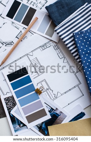 Interior designer\'s working table, an architectural plan of the house, a color palette, furniture and fabric samples in blue color. Drawings and plans for house decoration.