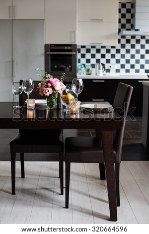 Dining table set with flowers, candles and glasses in the interior of modern kitchen