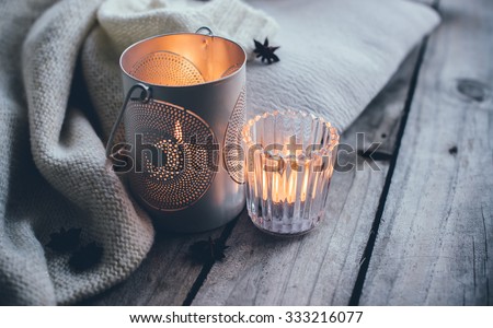 Cosy and soft winter background, knitted sweater and candles on an old vintage wooden board. Christmas holidays at home.