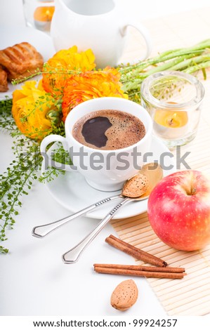 Elegant fresh breakfast: coffee, fruit, pastries, and flowers on a white background