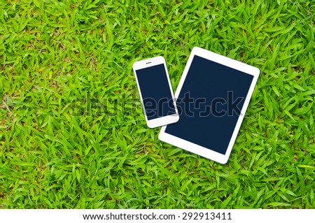 Tablet and Smartphone on green grass background with copy space,Responsive web design