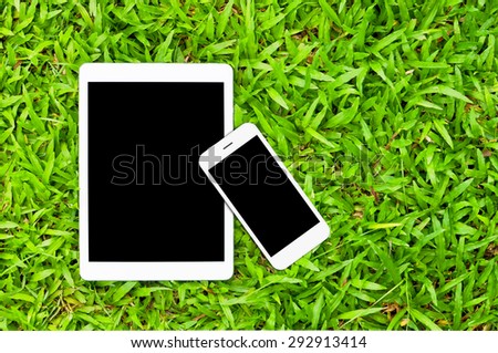 Tablet and Smartphone on green grass background with copy space,Responsive web design