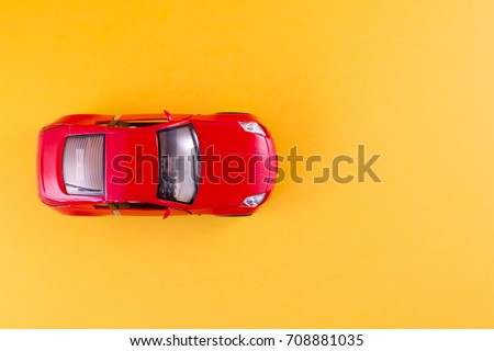 Toy red car on the yellow background top view