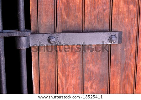 Horizontal image of the 1911 Shaniko Jail Cell Door hardware and bars and the wooden walls of the jail.