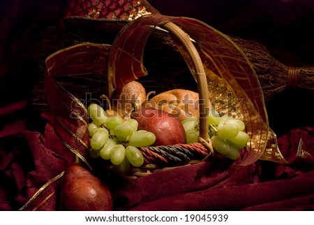 Still life of a basket of bread and fruit against a rich burgundy background, painted with light.