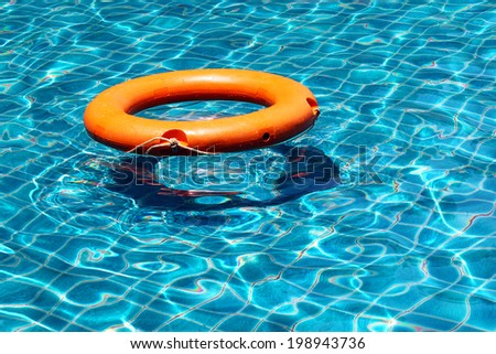 Orange life buoy is splashing with clear blue water in swimming pool, for the emergency case, use as the background and left the space for text