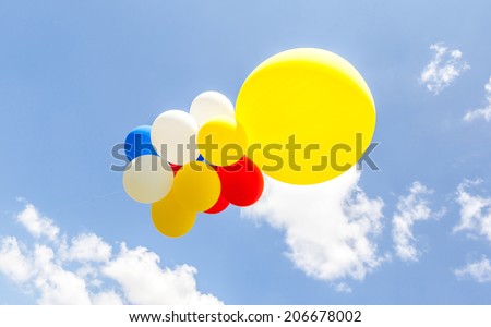 The big yellow balloon and other multicolored balloons against the blue sky