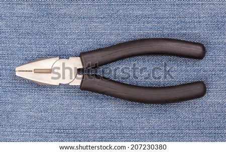 Pliers black handle tool isolated on blue jeans background for fixing and useful
