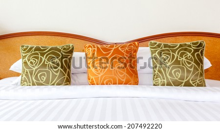 Hotel room setting with king sized bed, Thai silk orange and green pillows in Thailand hotel