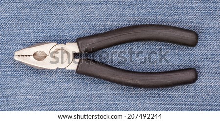 Pliers black handle tool isolated on blue jeans background for fixing and useful