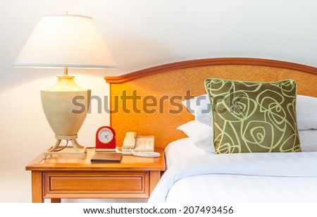 Hotel room setting with king sized bed, Thai silk green pillow, lamp, clock, telephone in hotel Thailand