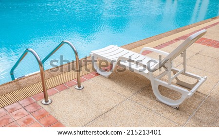 Relaxing beach chair beside grab bars ladder and blue swimming pool