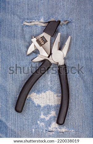 2 types of pliers black handle tool with torn blue jeans pattern background, concept for fixing and useful maintenance.