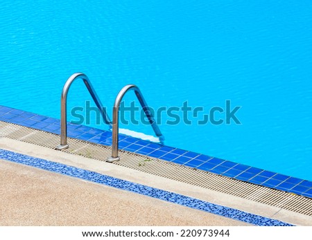 A view of a light clear blue swimming pool with steel ladder, outdoor swimming pool.