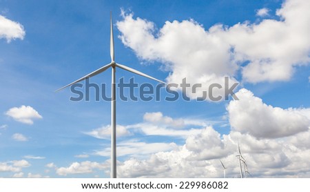 The giant wind turbine stands against cloudy blue sky background in wind farm Thailand, clean energy concept.