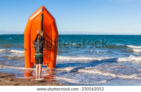 The young man lifeguard is pushing rescue rubber boat on the sea, concept of security on beach.