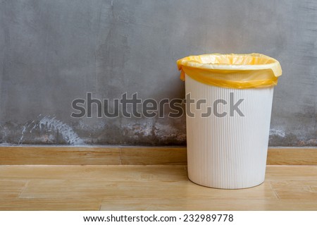 The white plastic bin with orange bag on wooden floor with exposed cement background, for cleaning and recycle.
