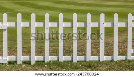 White wooden fence in farm field marks for land property.