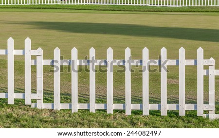 White wooden fence in farm field marks for land property.