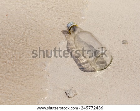 Glass bottle and small corals on beach sand, environment problem needed to help.