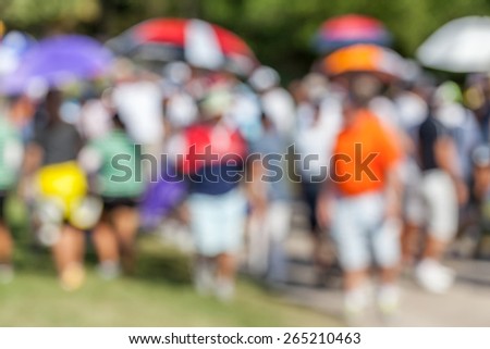 Blurred photo of golfer and audience on green in golf tournament.