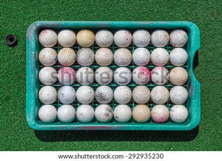 Roll of grunge golf balls in tray on green